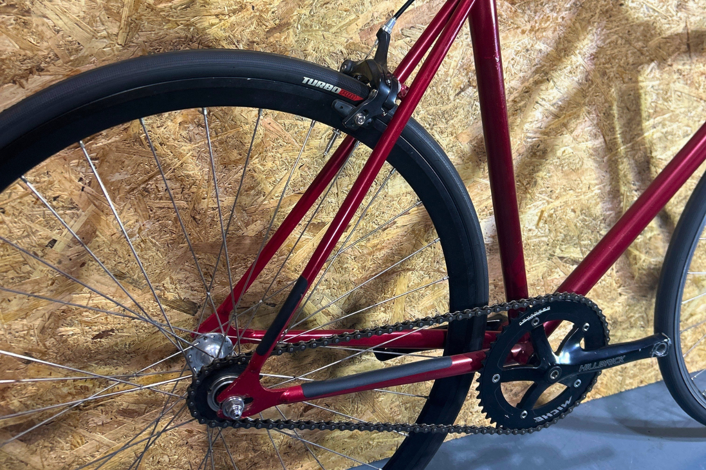 Close-up of a red bicycle with chain and gear on a textured brown background