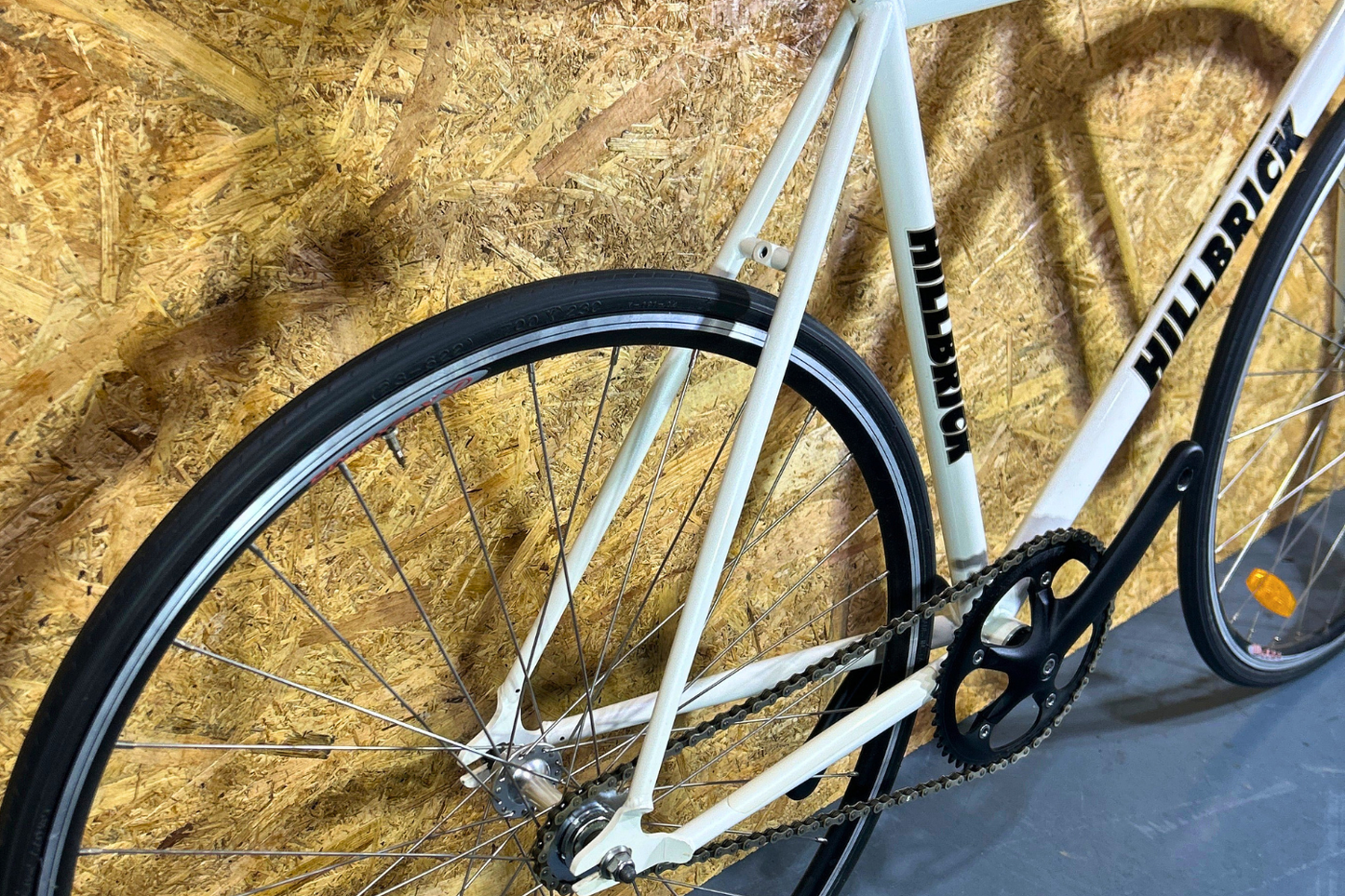 White bicycle with black tires against a wooden panel background