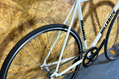 White bicycle with black tires against a wooden panel background
