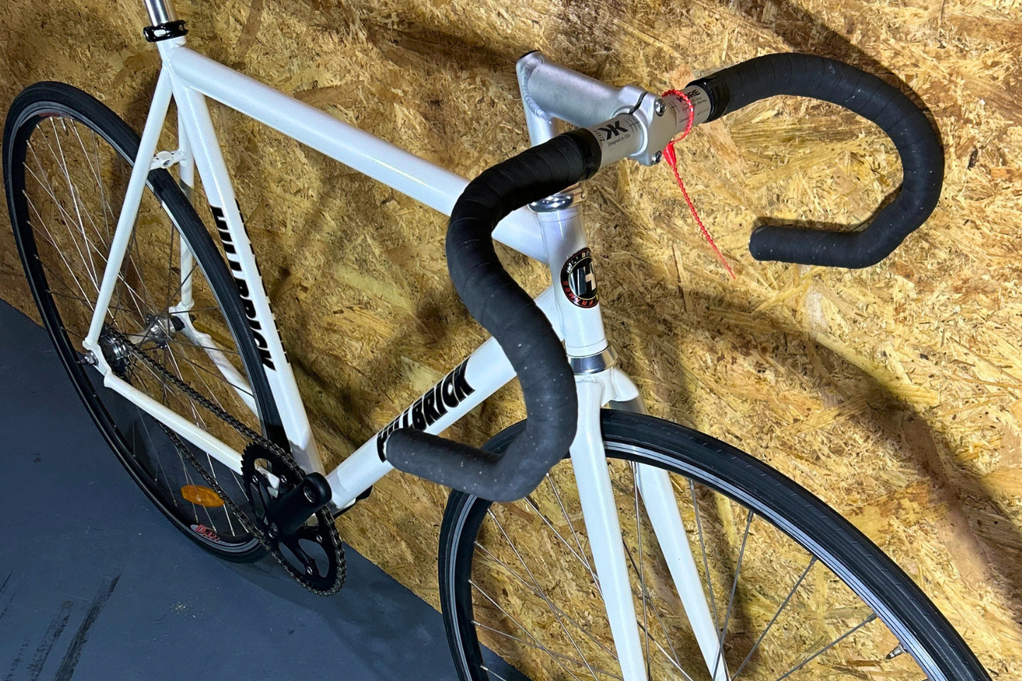 White bicycle with black handlebars against a textured wall.